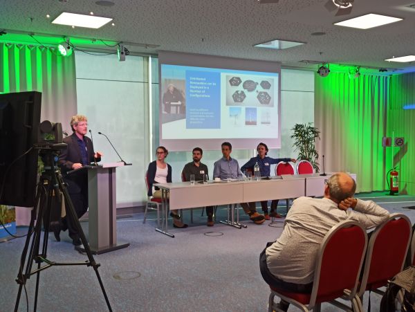 Ian Baring-Gould (NREL, Task 41) hält einen Vortrag über die Rolle von dezentraler Windenergie bei der Unterstützung der Energiewende. Weitere Redner auf dem Podium von links nach rechts: Franziska Gerber (Meteotest, Task 54), Charles Goudreau (Nergica, Task 54), Andreas Krenn (Energiewerkstatt), Claas Rittinghaus (Energiewerkstatt, Task 54).